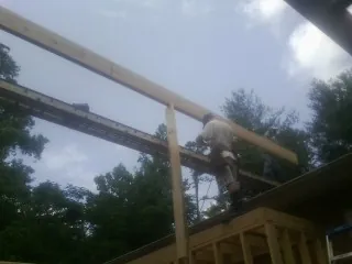 Carpenter setting a ridge beam over a new addition frame — Ice Dam Removal by Roofing Brothers in Schoolcraft