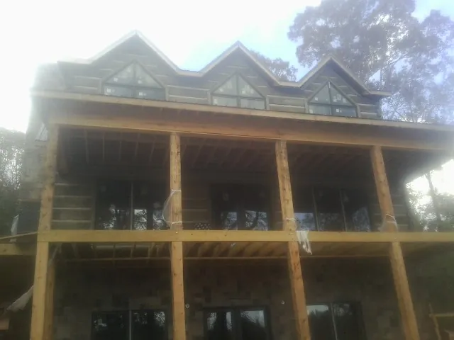 Dormers and porch framing on a large log home under construction — Roof Coating work by our crew in Schoolcraft