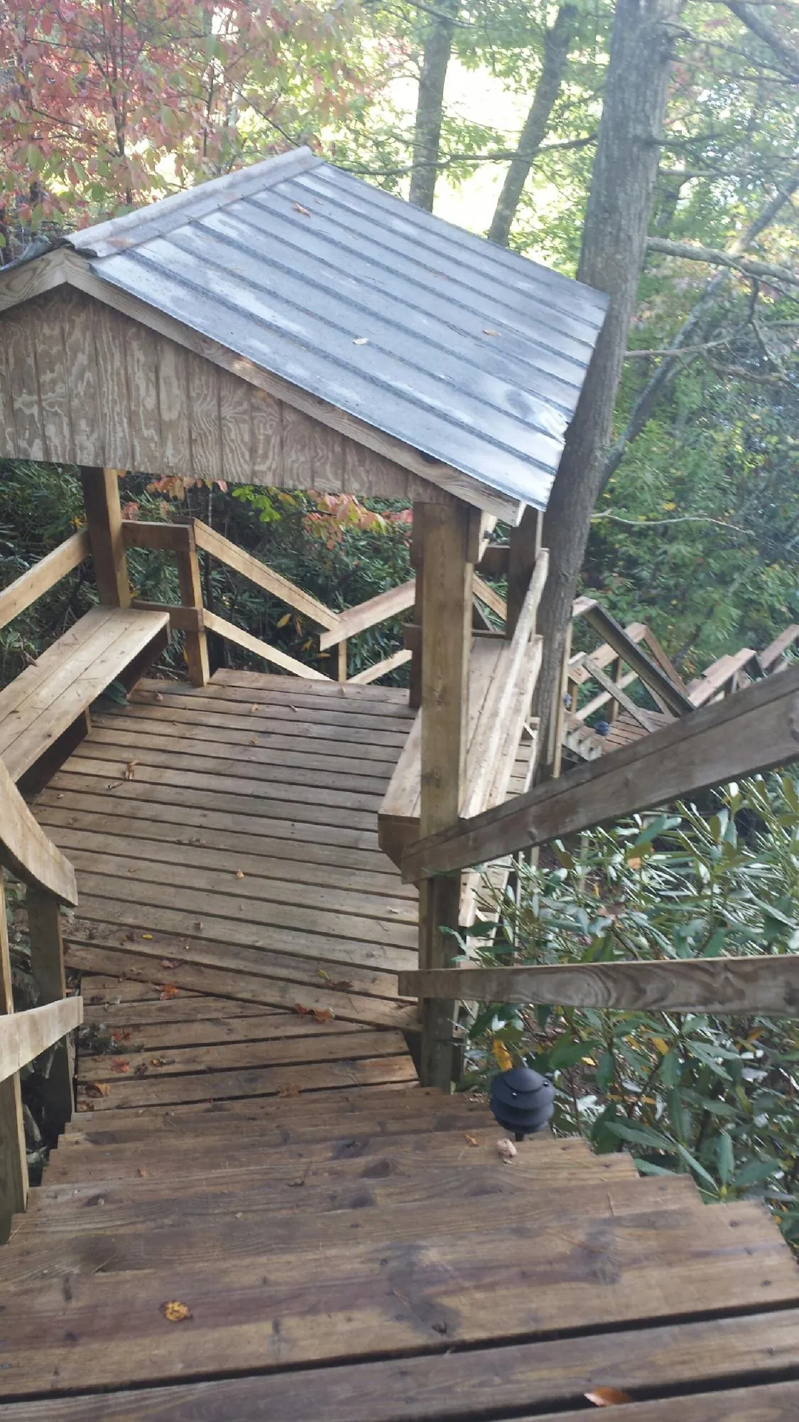 Metal roofed shelter over wooden steps on a wooded walkway — Skylight Repair & Installation work by our crew in Schoolcraft