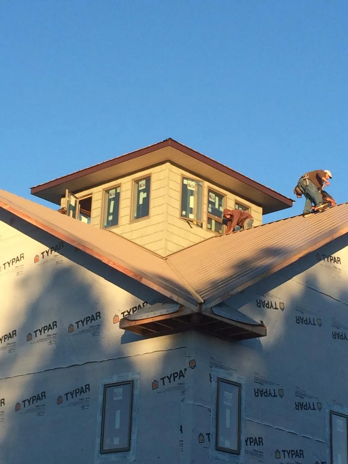 Roofers working around a rooftop cupola on a new metal roof at sunset — Roof Waterproofing in Schoolcraft by Roofing Brothers
